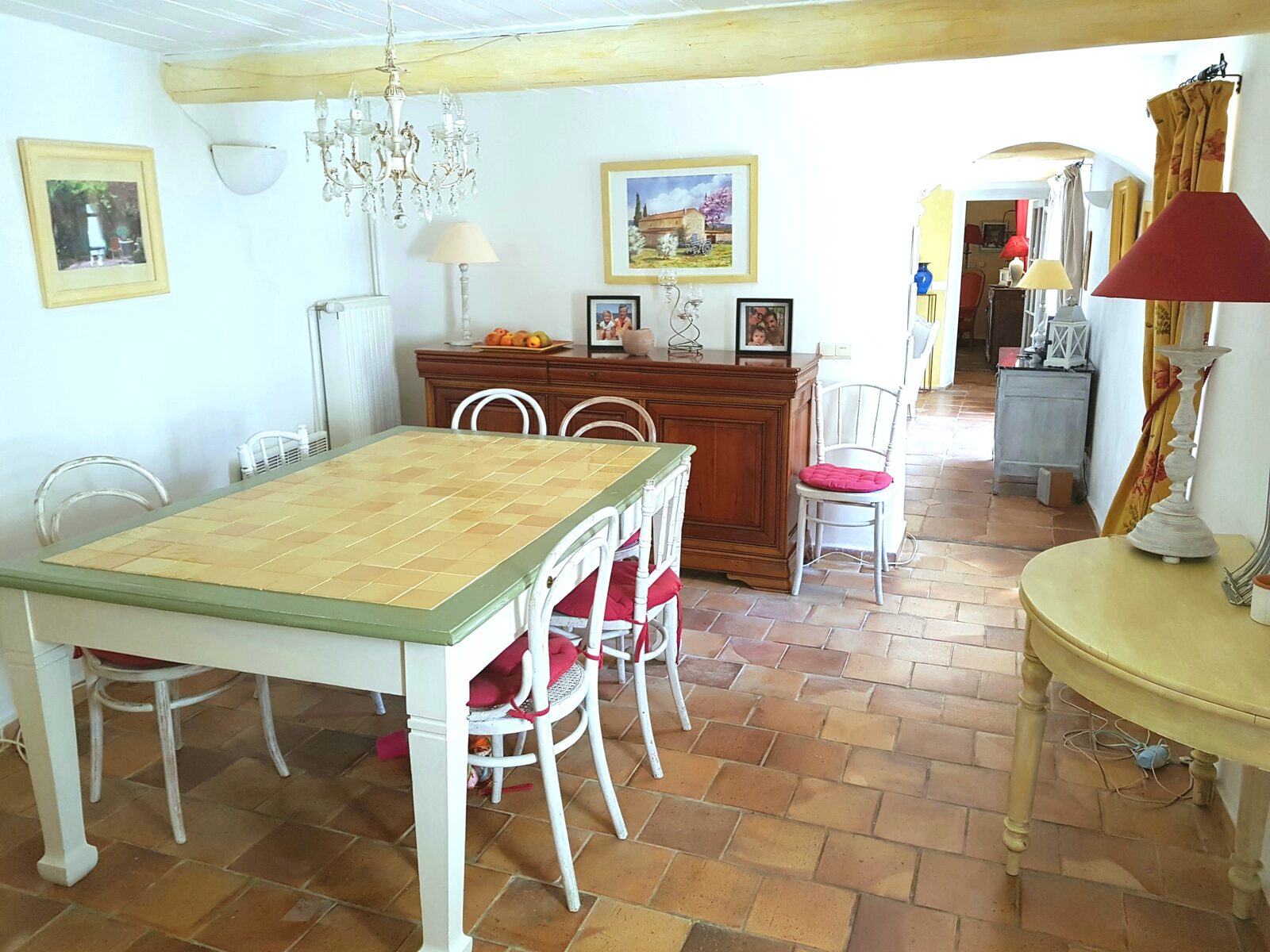 Salle à manger provençale avec table aux carreaux jaunes, tomettes anciennes et lustre